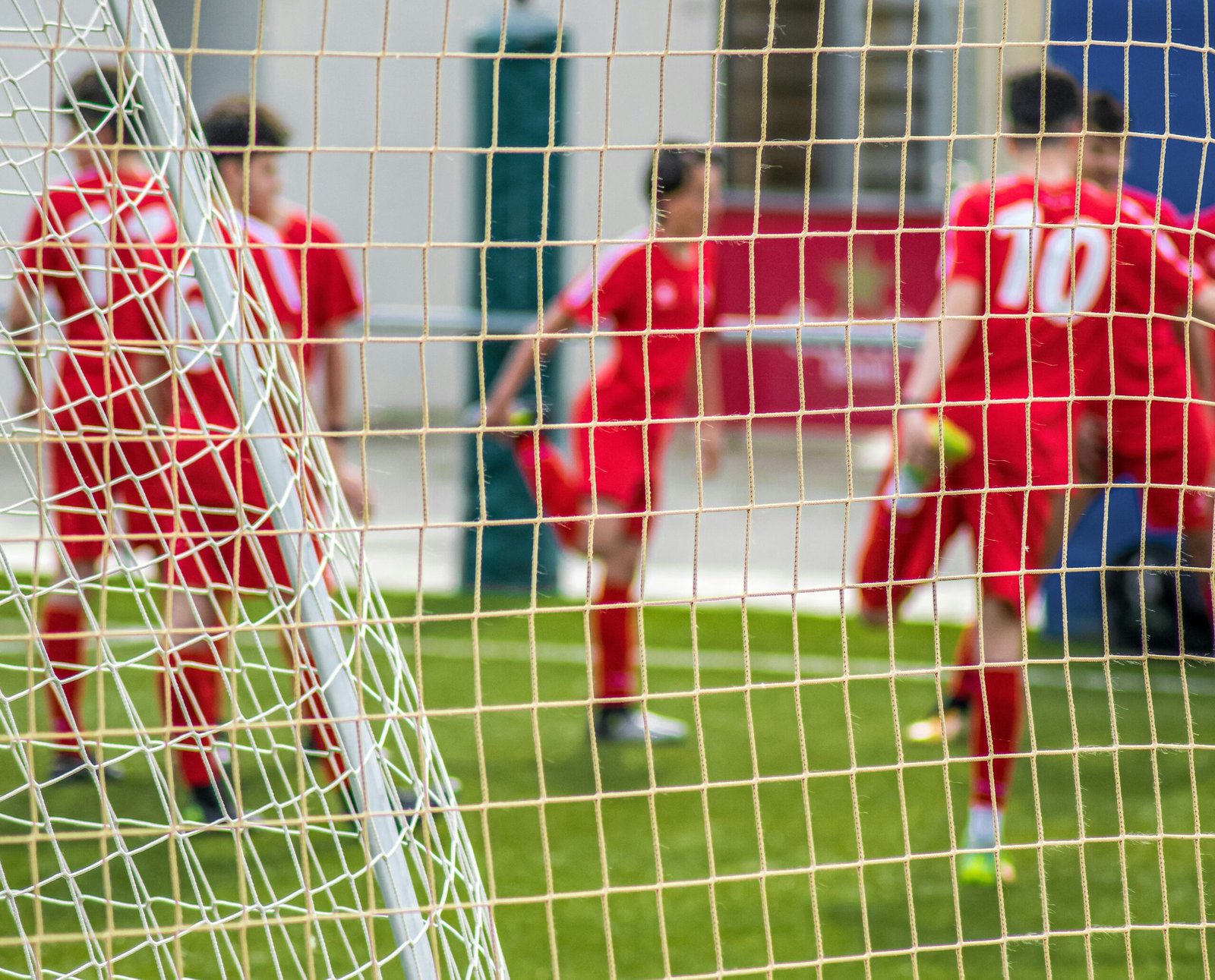 soccer players in red jersey shirt playing soccer during daytime